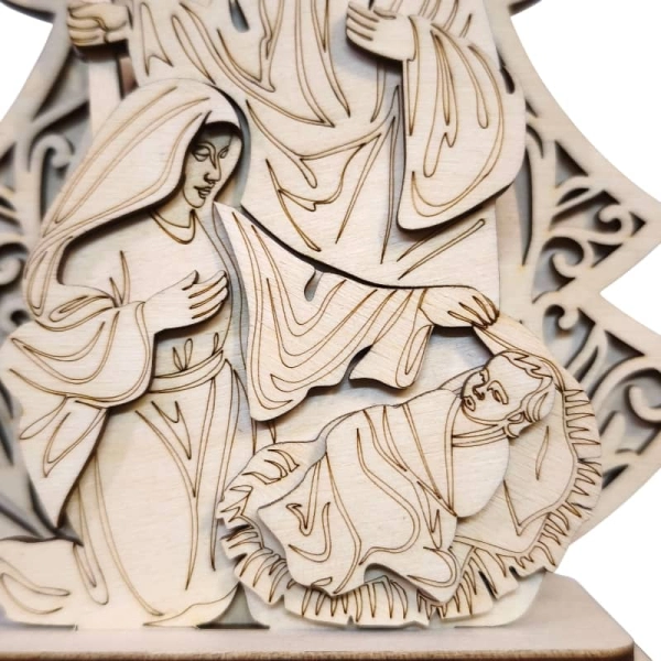 Zbliżenie na ażurową choinkę z wyciętym aniołem oraz postacie Świętej Rodziny.