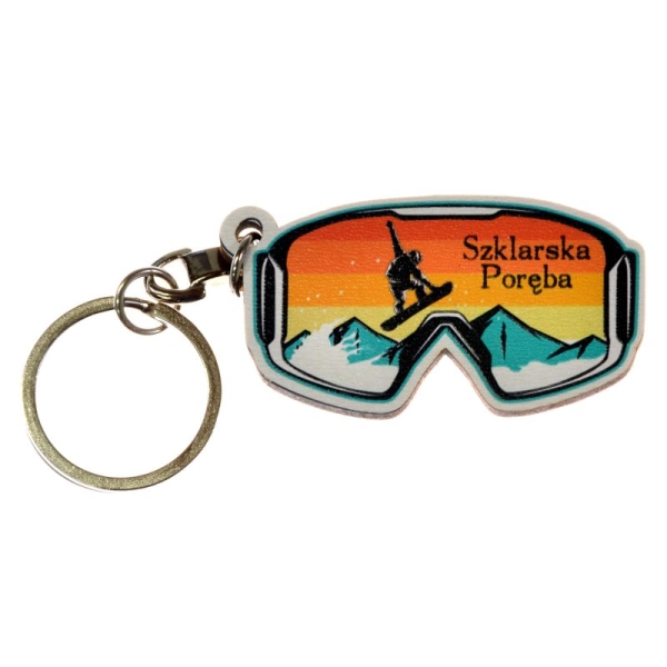 Breloczek w kształcie kształcie okularów snowboardowych z grafiką gór oraz snowboardzisty. 