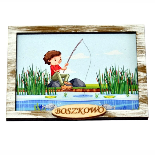 Drewniany magnes na lodówkę przedstawia siedzącego chłopca wędkującego nad brzegiem jeziora.