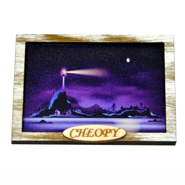 Pamiątka regionalna jaką jest magnes na lodówkę przedstawia latarnię morską na wzgórzu świecącą nocą.