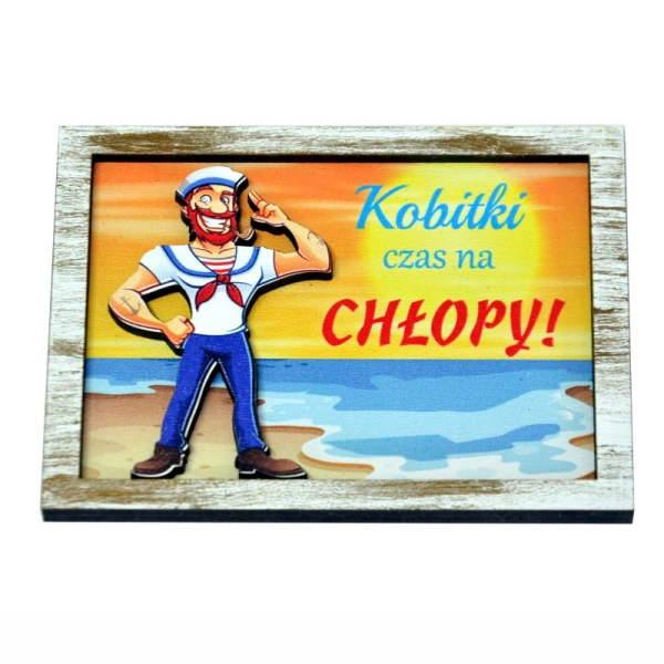 Drewniany magnes na lodówkę z marynarzem przyklejonym na tle przedstawiającym zachód słońca nad morzem.