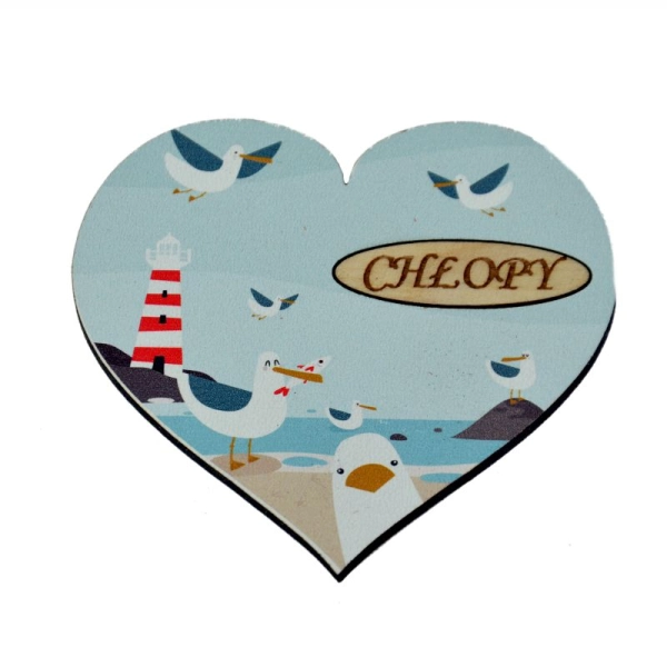 magnes serce ze stadem mew na nadmorskiej plaży, w tle widać latarnię morską.